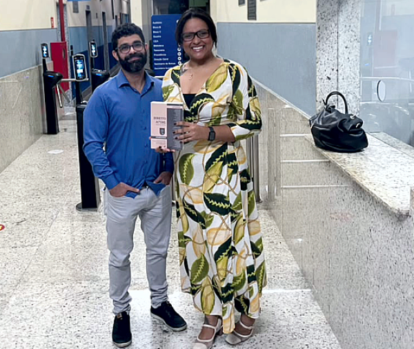 Professor Ronaldo Félix entrega à egressa Diulya Évilyn o livro com capítulo coautorado, fruto do TCC dela sobre redes sociais e liberdade de expressão. Foto: Divulgação.